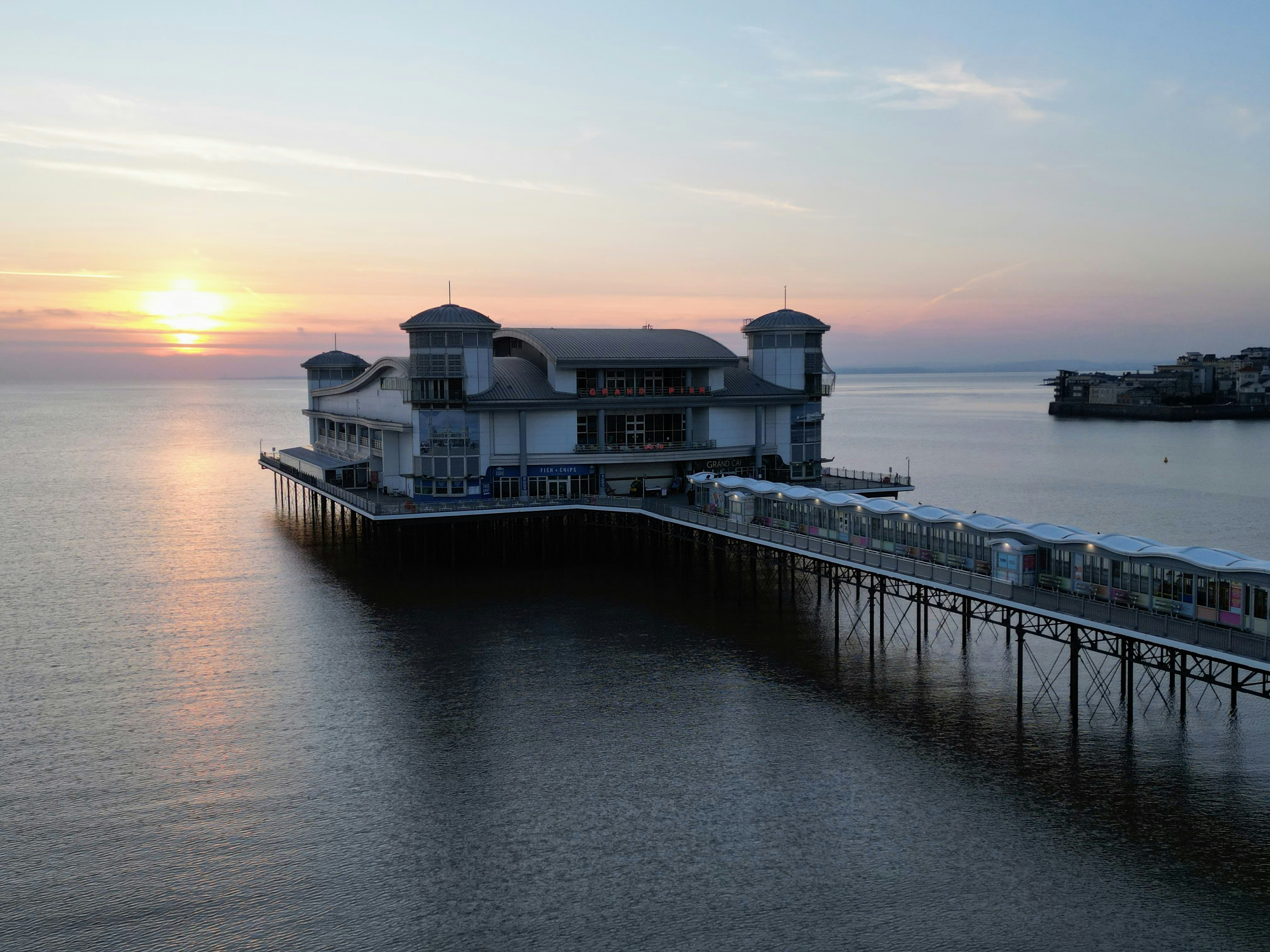 a pier with a restaurant on it in the middle of the ocean