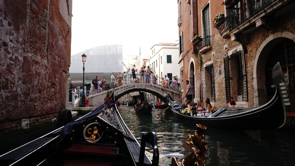 a group of people riding on top of a boat down a canal