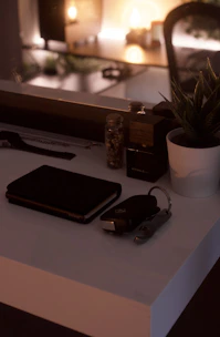 A tidy desk with a journal, a warm cup of tea, and a small potted plant near a softly glowing lamp.