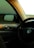 A car's interior featuring a steering wheel with a Volkswagen logo, the side view mirror, and part of the dashboard is visible. Soft lighting casts a golden glow on the surfaces.
