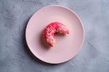 A close-up of a pastel pink squishy donut with colorful sprinkles, softly squeezed in a hand.