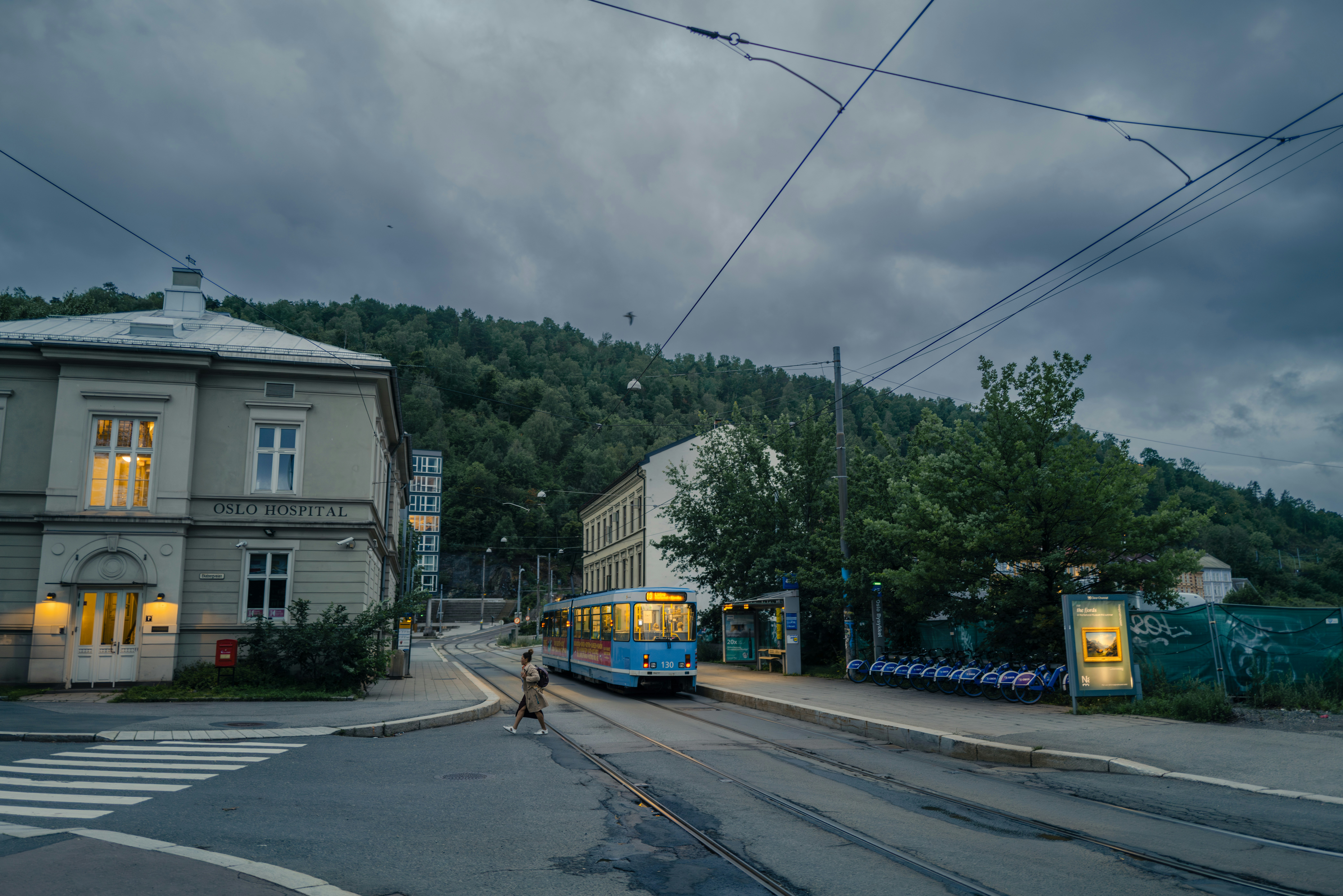 a blue and yellow bus driving down a street next to a tall building