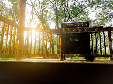 A technician assembling a stainless steel outdoor grill on a sunny patio.