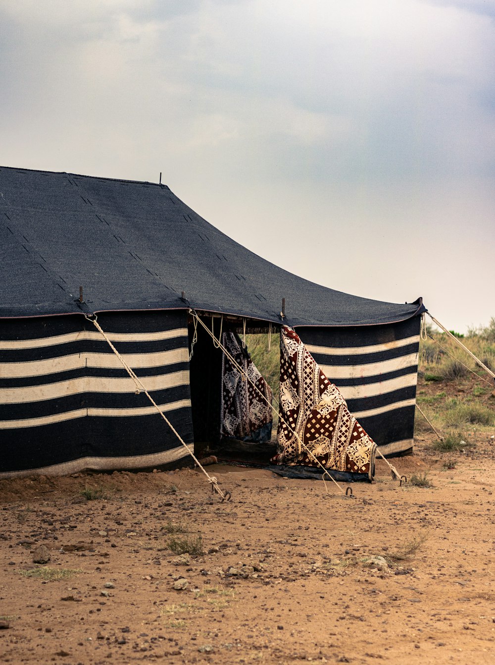 a black and white striped tent sitting on top of a dirt field