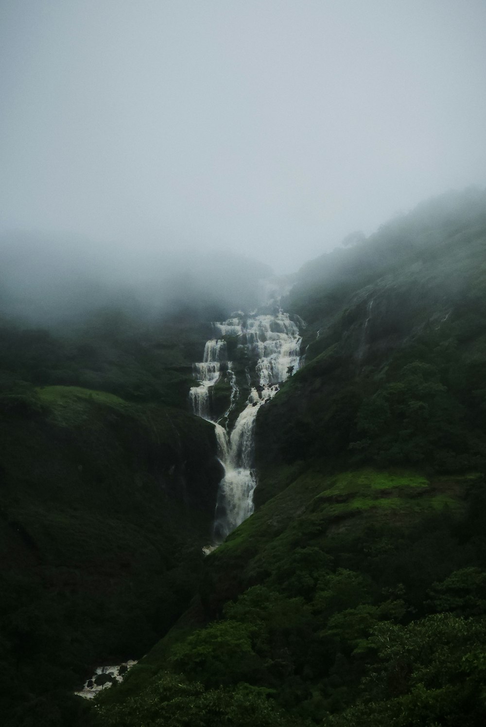 a waterfall in the middle of a lush green valley