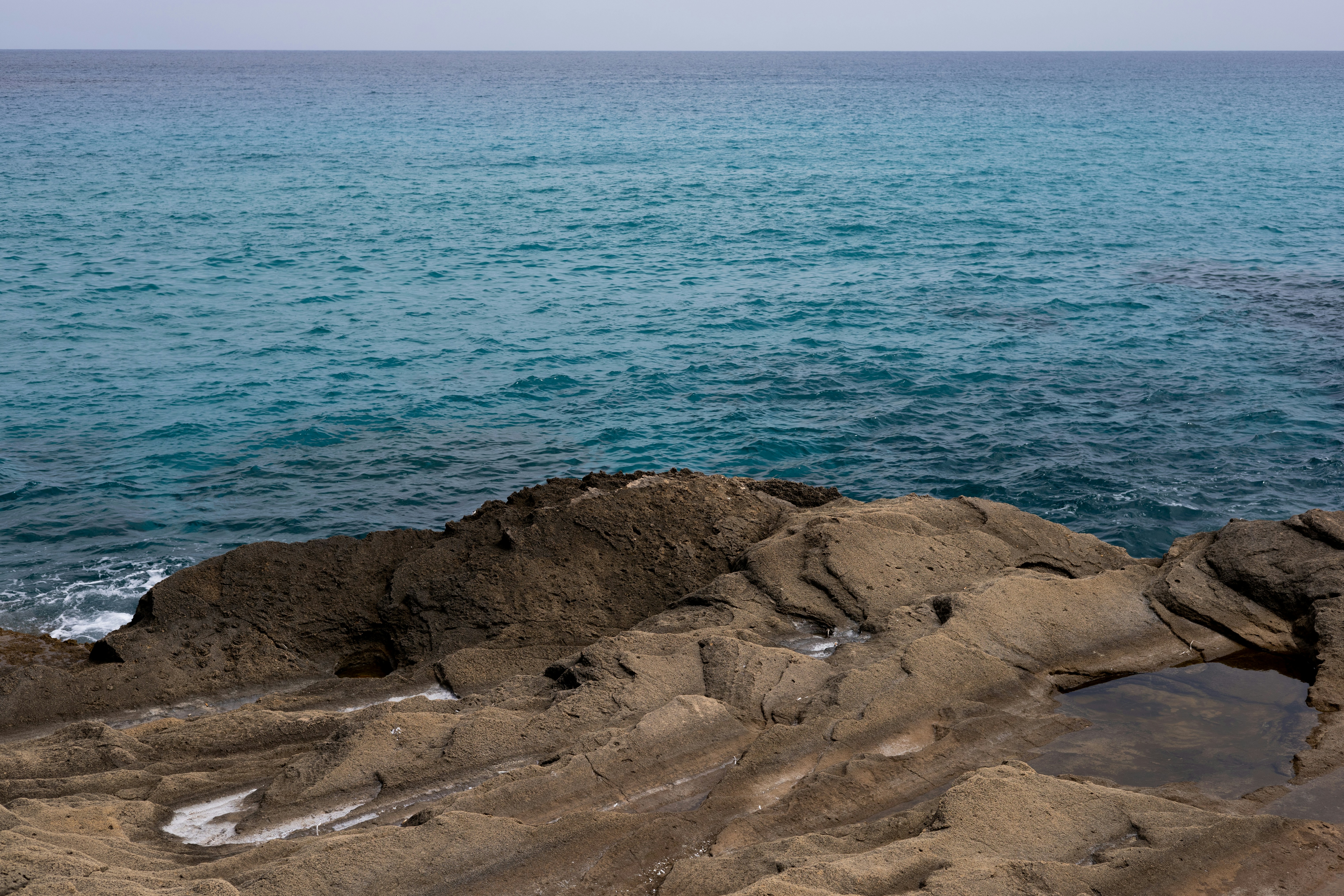 a large body of water sitting next to a rocky shore