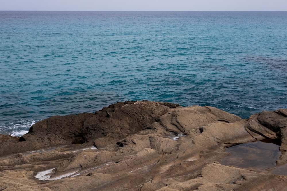 a large body of water sitting next to a rocky shore