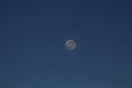 A clear, high-resolution view of the moon against a dark blue sky, with the moon's surface features visible.