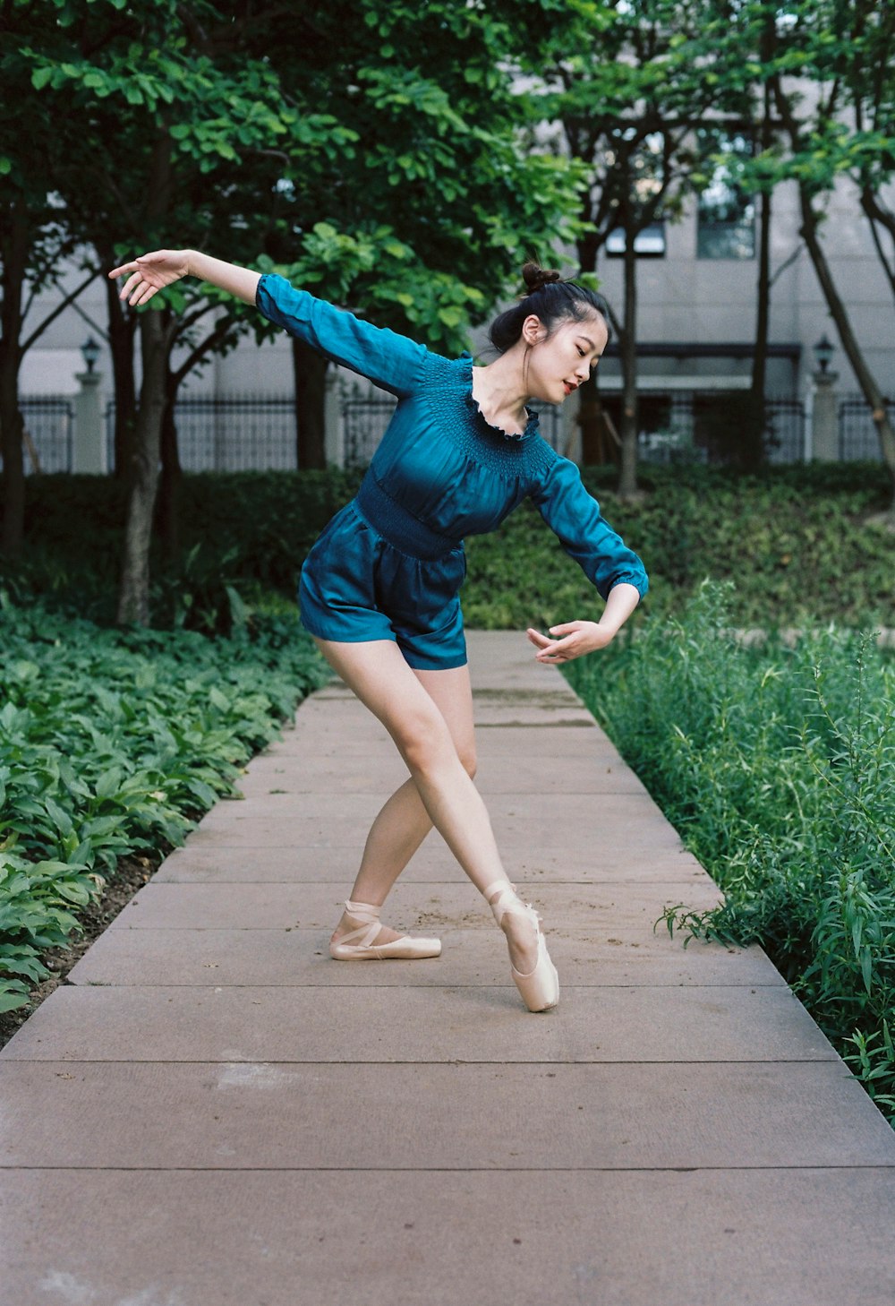 a woman in a blue dress is dancing on a sidewalk