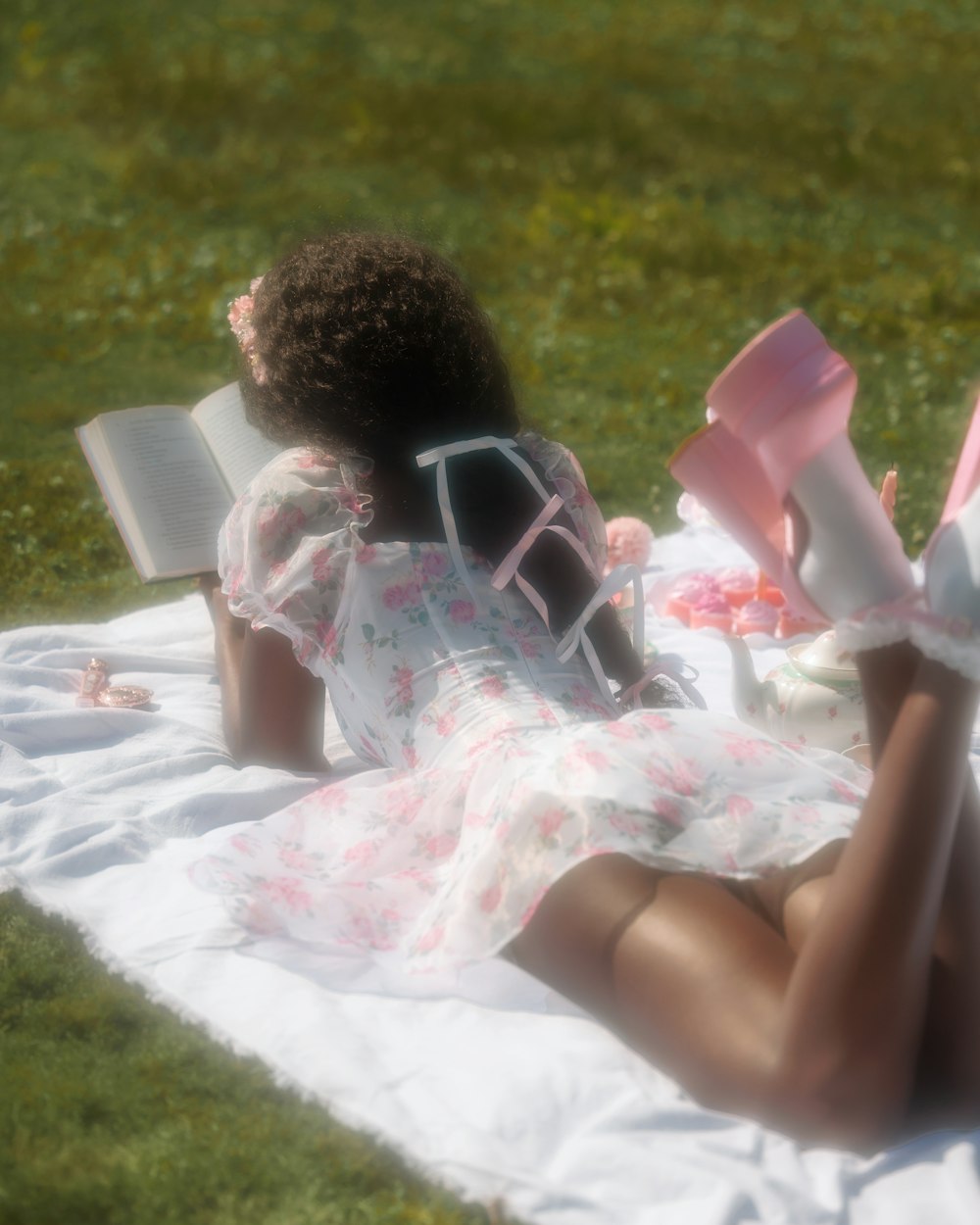 a woman laying on a blanket reading a book