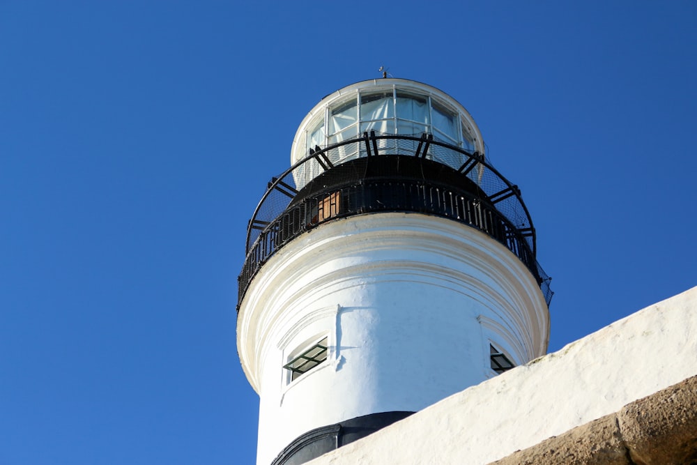 a white and black lighthouse against a blue sky