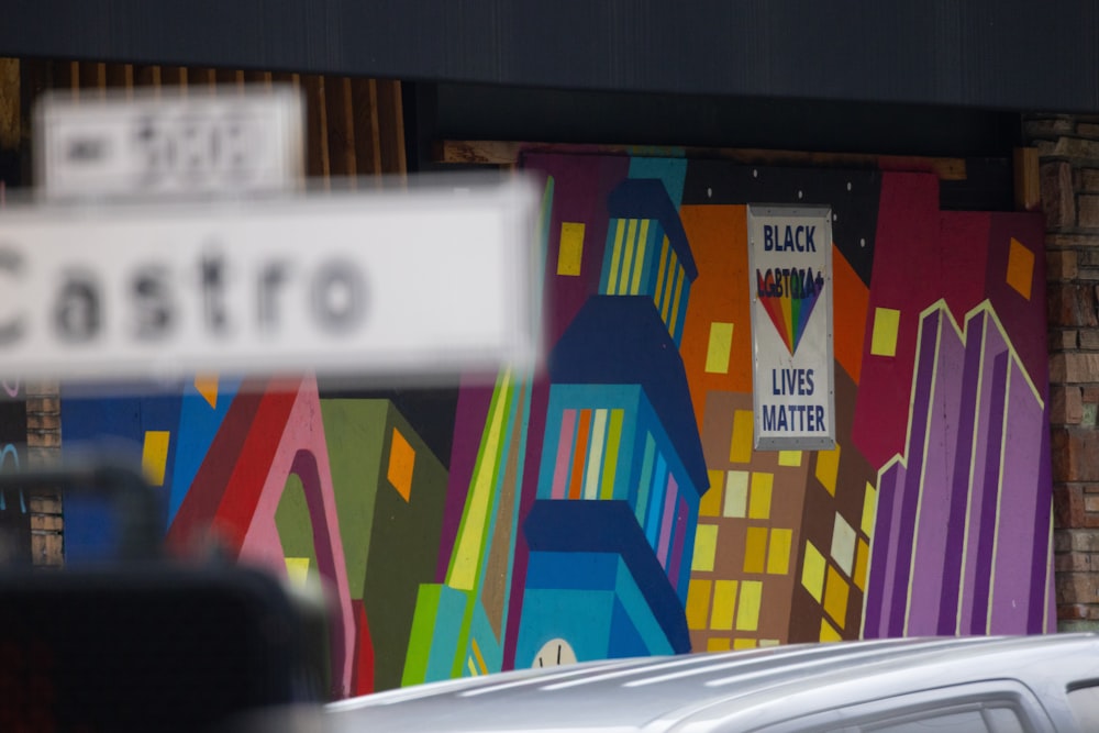 a white car parked in front of a colorful wall