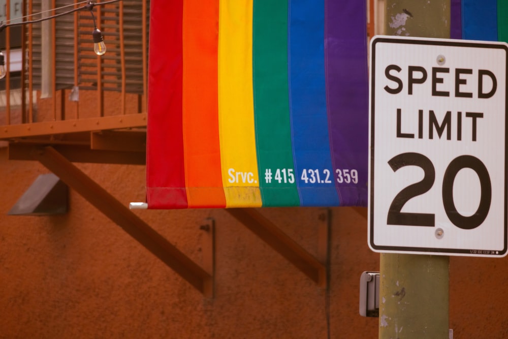 a speed limit sign next to a rainbow flag