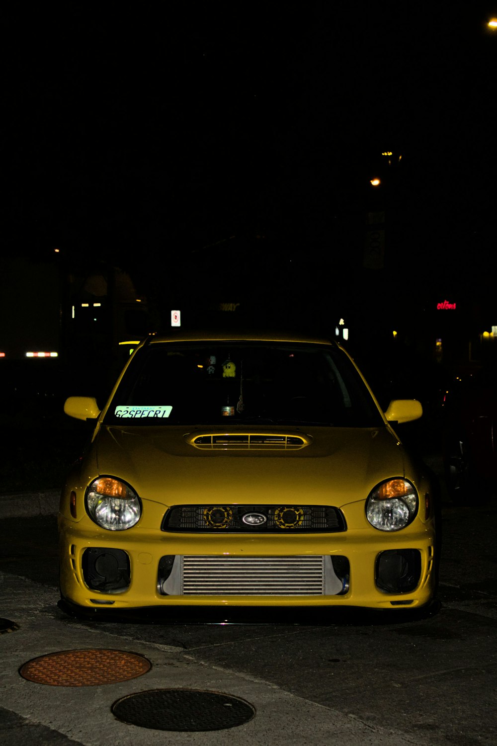 a yellow car parked in a parking lot at night