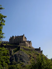 Ancient stone castles nestled in lush green landscapes under a clear sky.