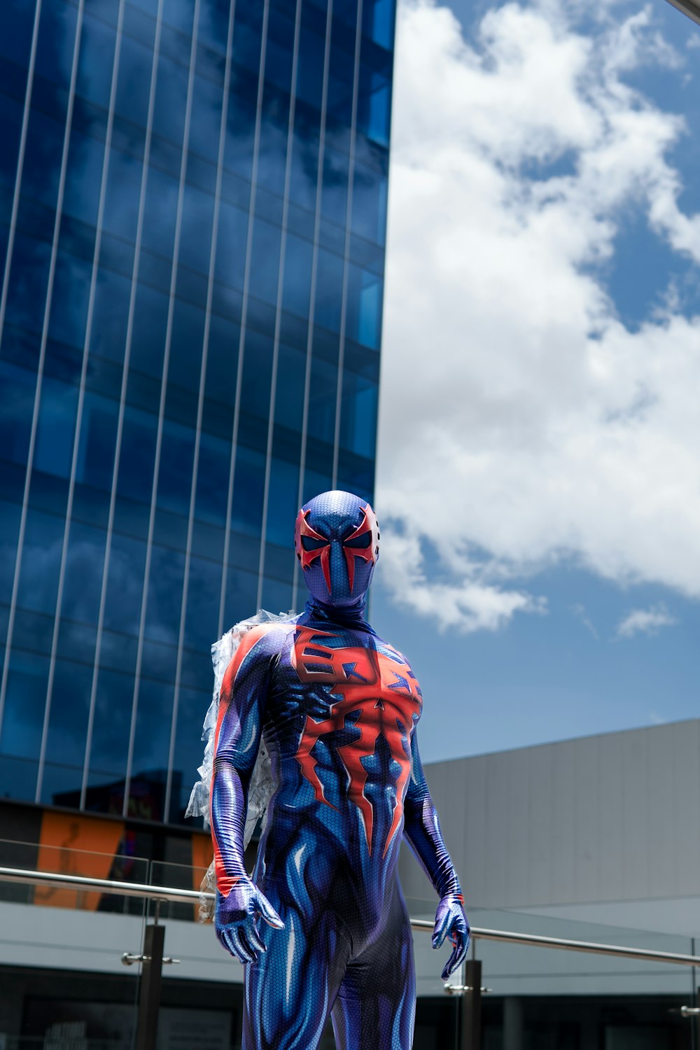 a man in a blue and red suit standing in front of a building