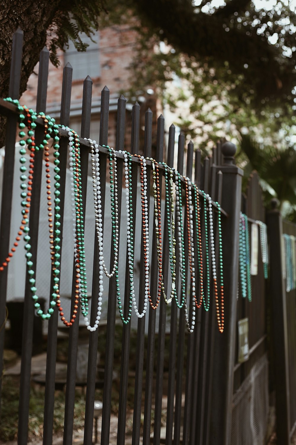 a bunch of beads are hanging on a fence