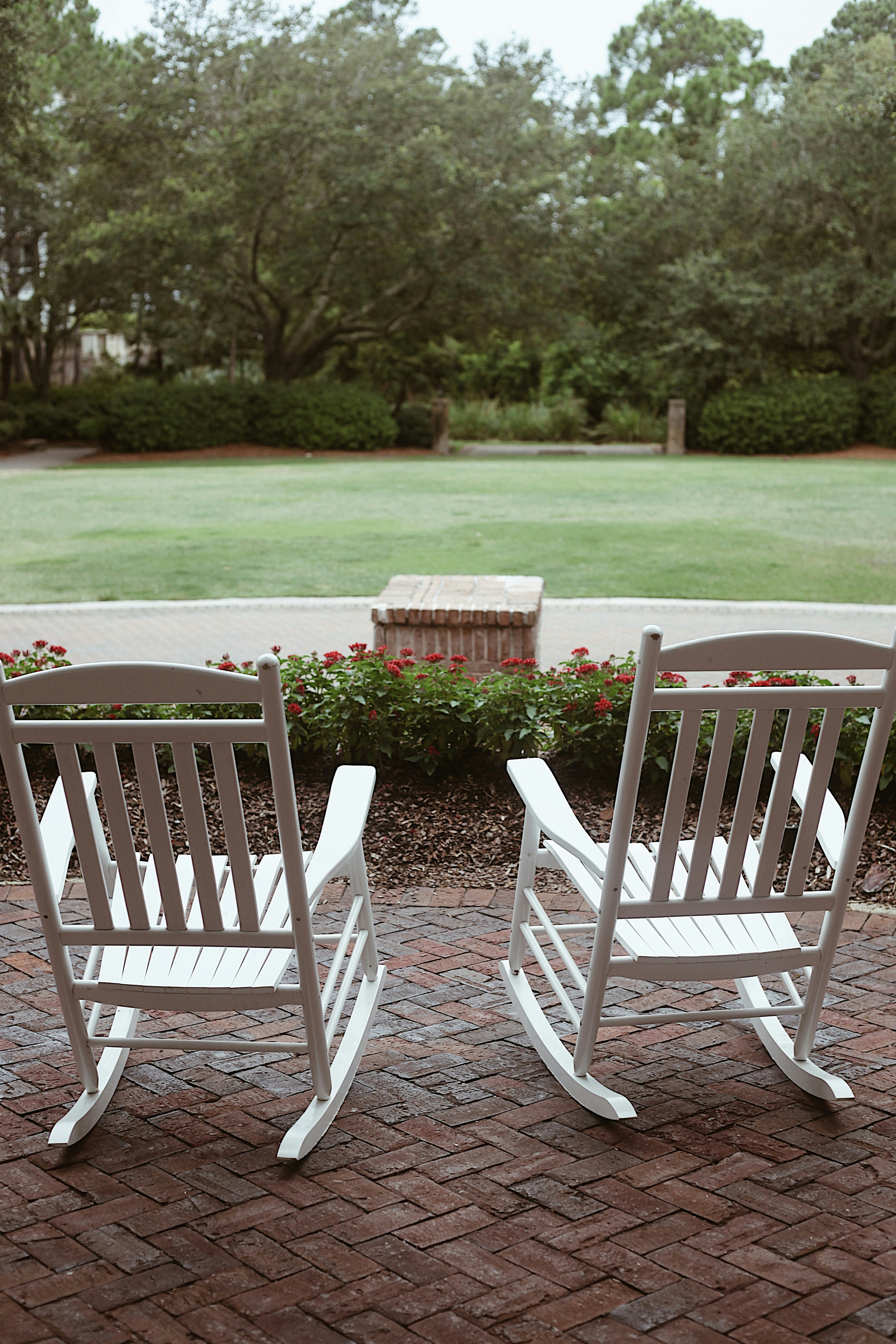 a couple of white rocking chairs sitting on top of a brick patio