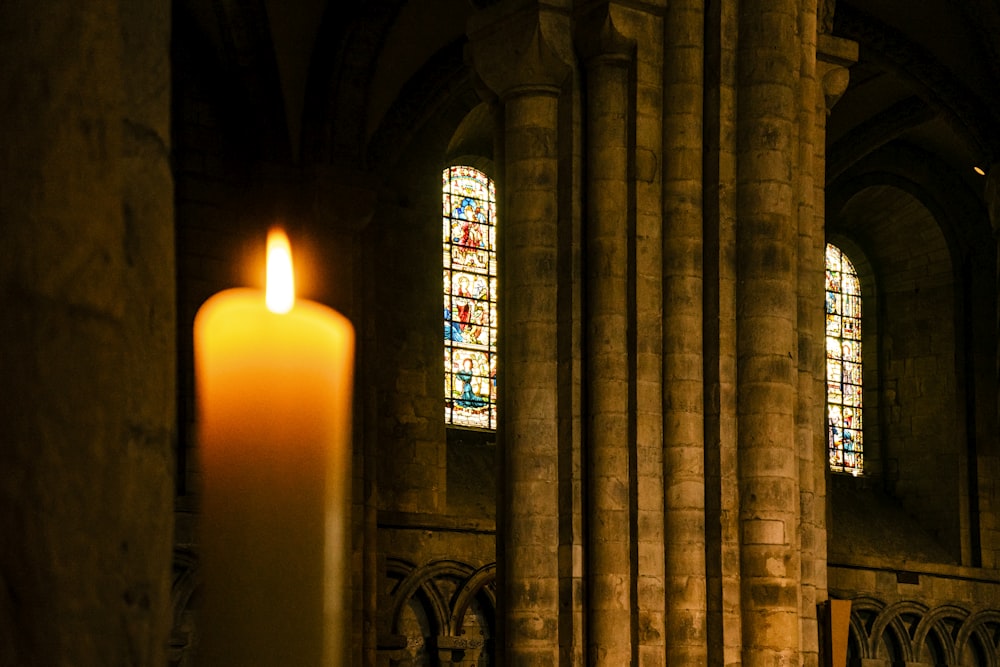 a candle in front of a stained glass window