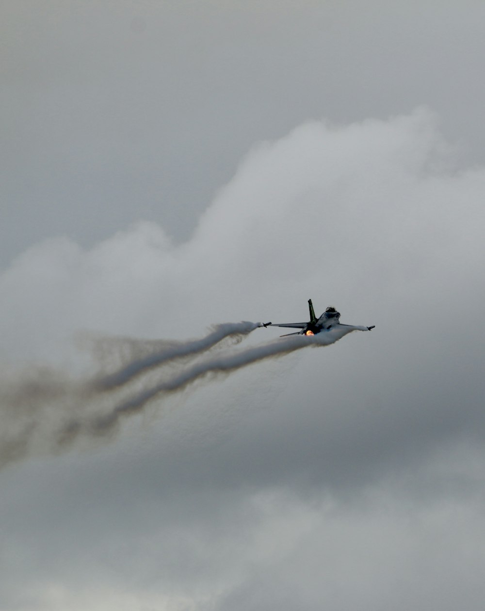 a plane flying in the sky with smoke coming out of it