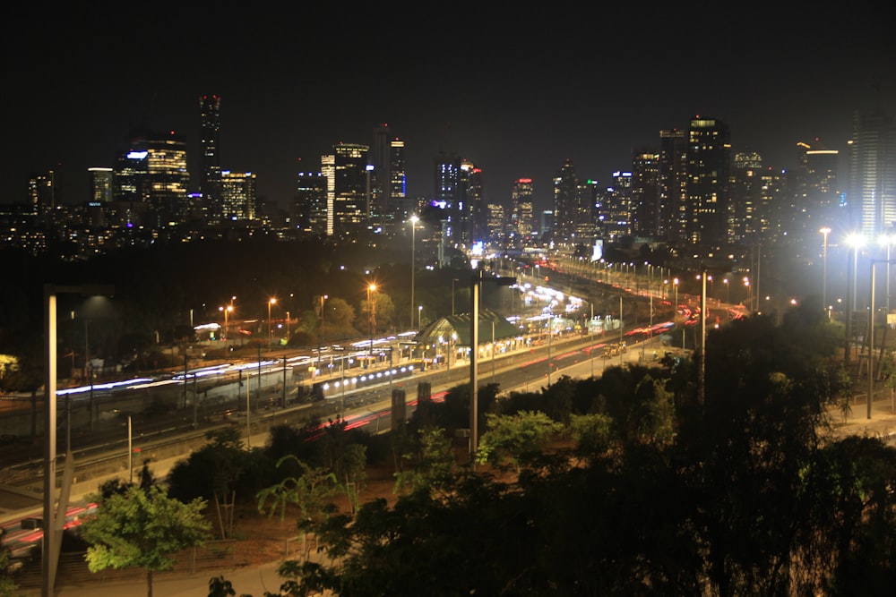 a city skyline at night with a train on the tracks