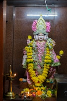 A close-up of an intricately carved statue of Maha Guru Shree Dattatreya surrounded by blooming flowers.