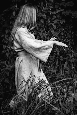 a black and white photo of a woman standing in tall grass