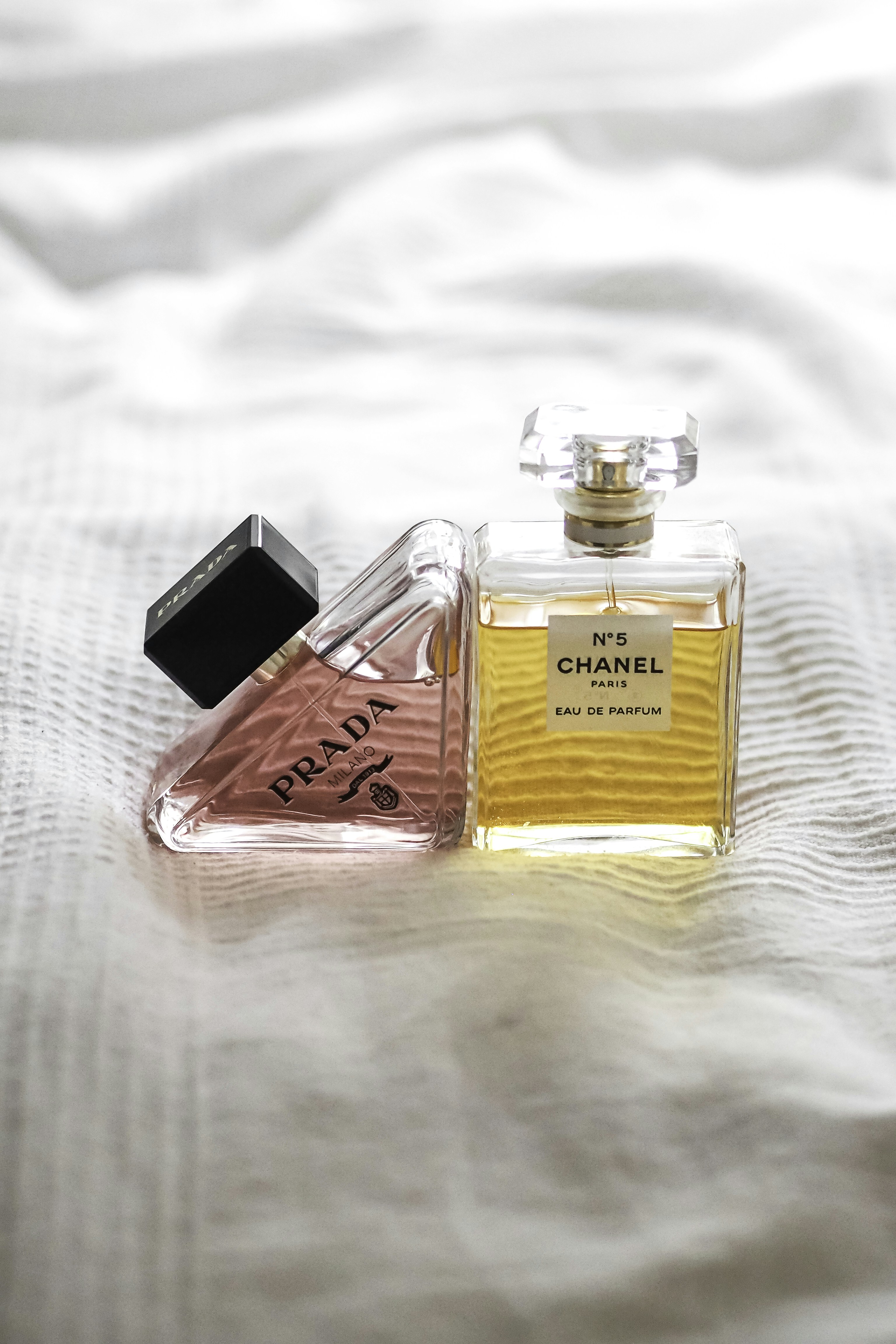 two bottles of perfume sitting on top of a bed