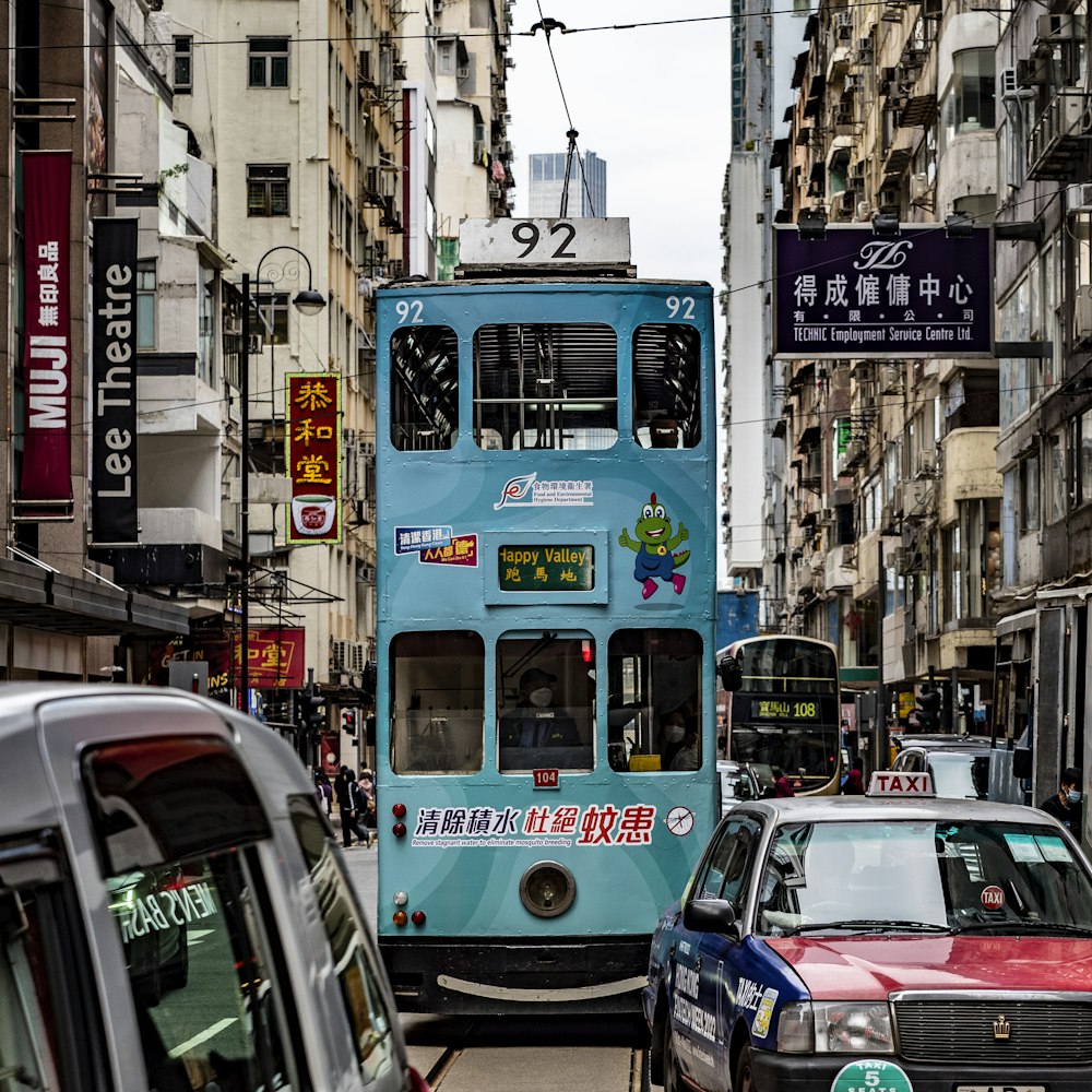 a blue double decker bus driving down a street