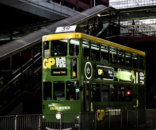 a green double decker bus driving down a street