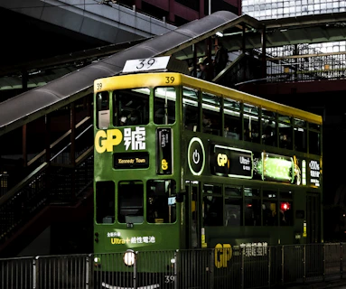 a green double decker bus driving down a street