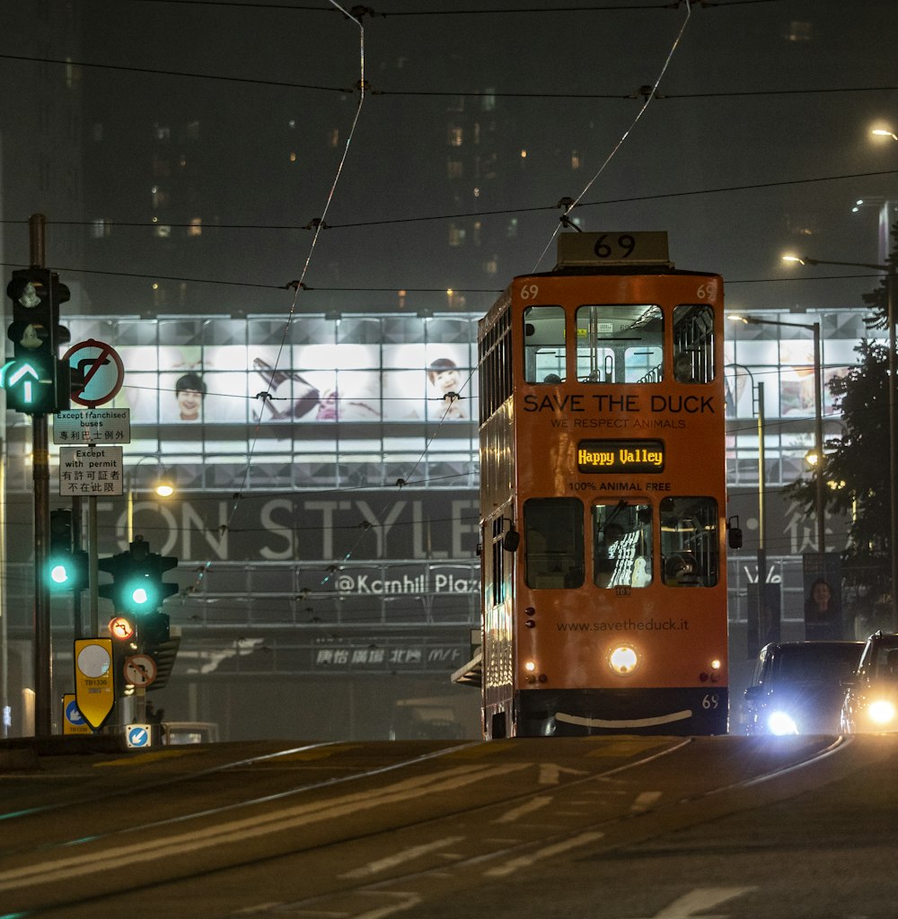 a double decker bus driving down a street at night