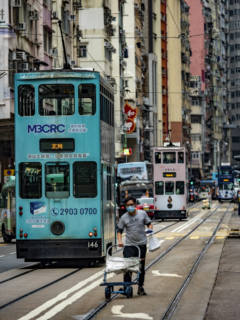 a blue double decker bus driving down a street