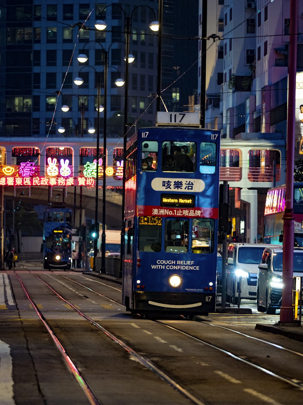 a blue double decker bus driving down a street