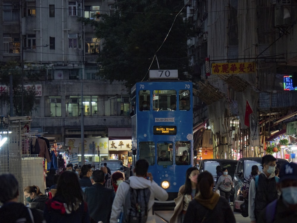 a blue double decker bus driving down a busy street