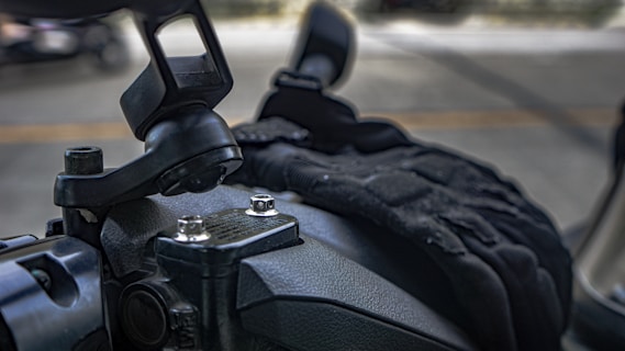 A close-up of a motorcycle's handlebar area showing the mounting bracket for an accessory. The background is blurred, indicating a shallow depth of field.