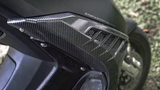 Custom carbon fiber dirt bike parts displayed on a workbench with tools.