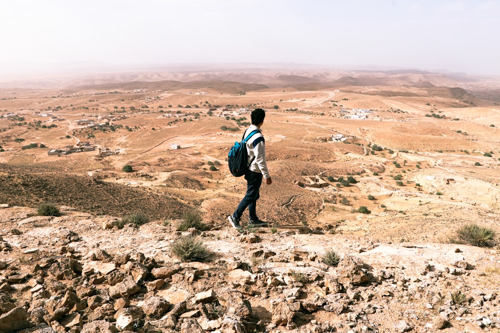 a man with a backpack standing on top of a mountain