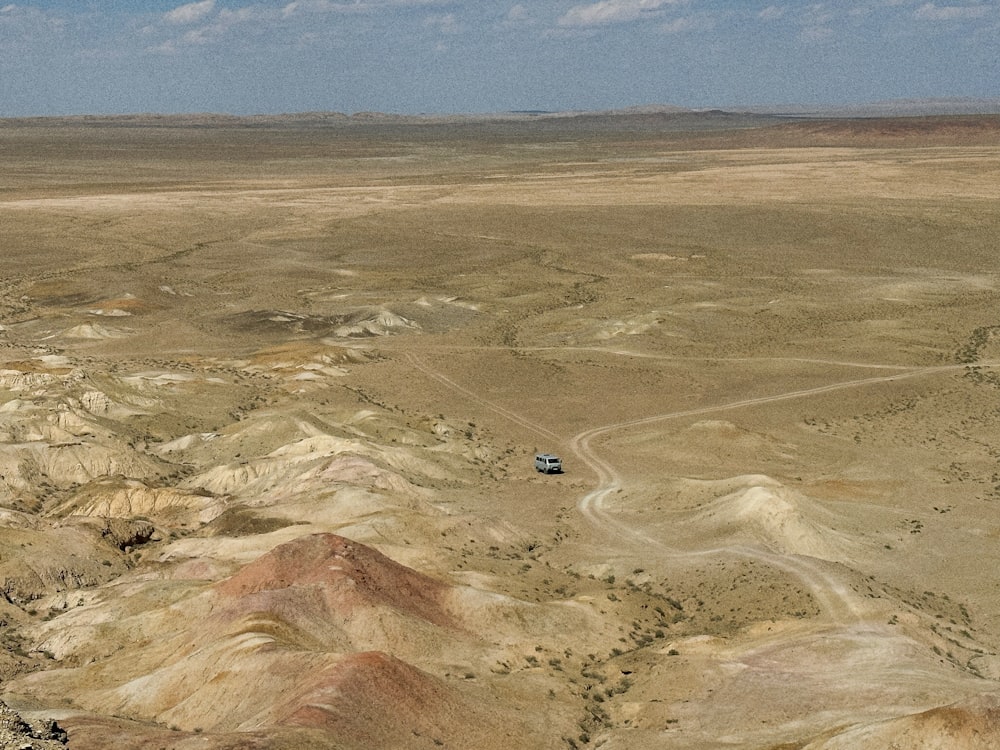 an aerial view of a desert with a vehicle driving through it