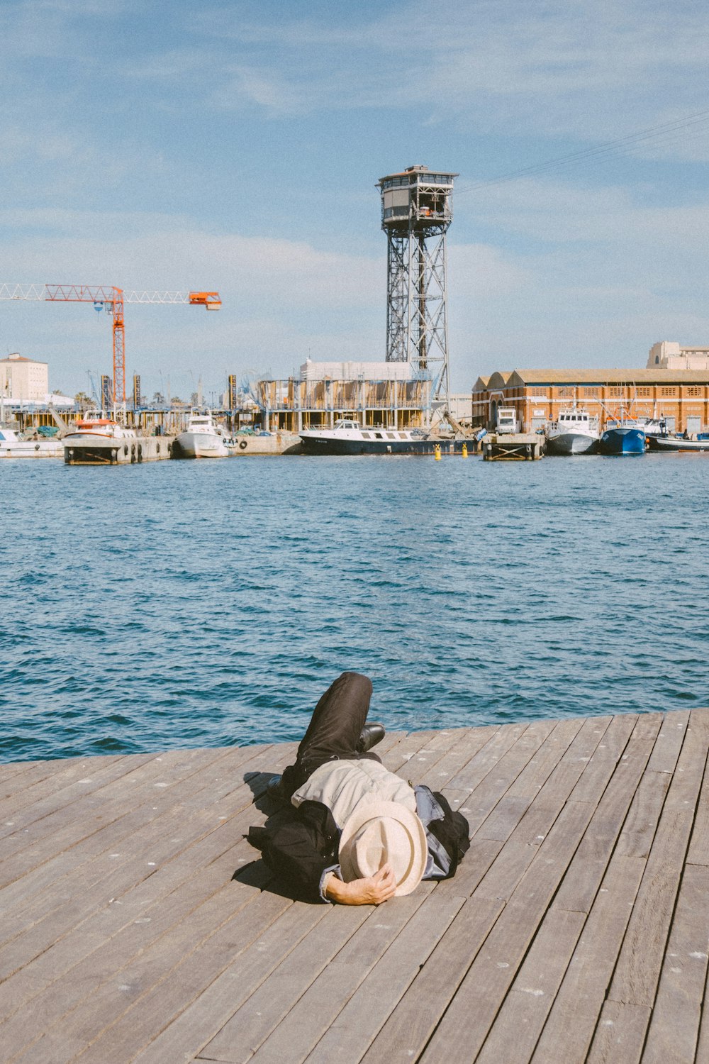 a person laying on a wooden dock next to a body of water
