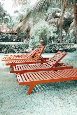 A group of friends relaxing on various colorful folding lounge chairs at a backyard barbecue.
