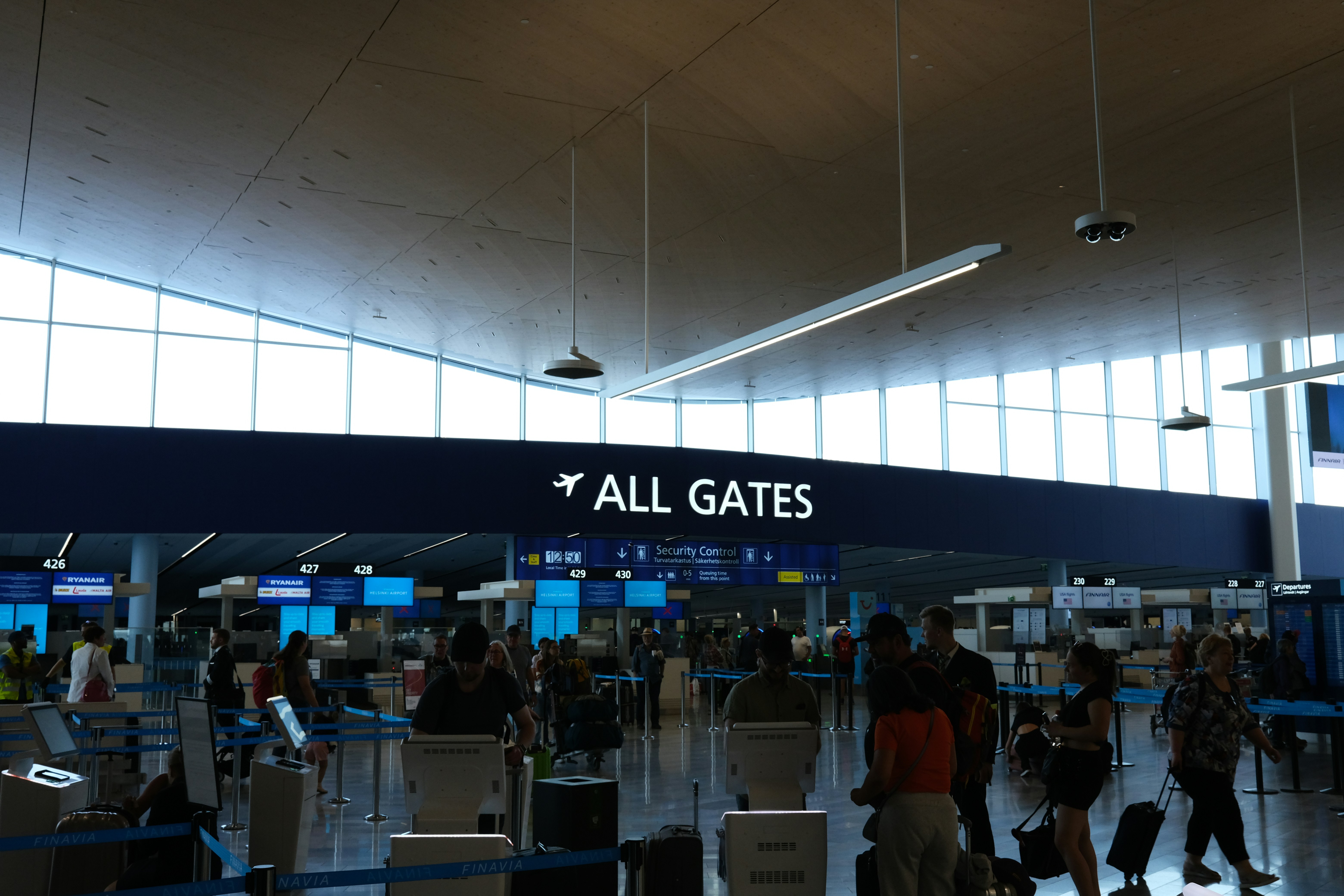 a group of people walking through an airport, Helsinki airport terminal 2023.