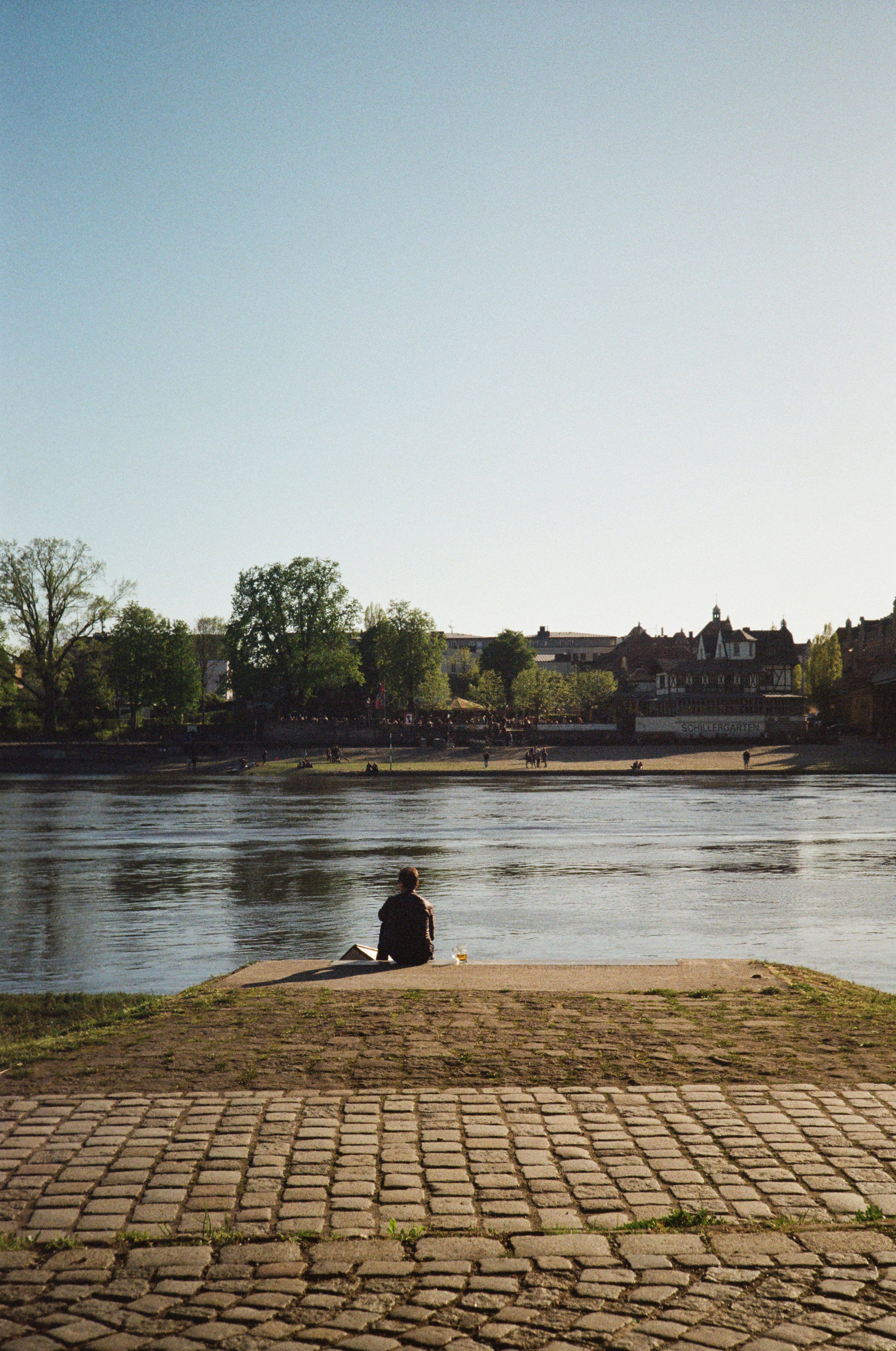 a man sitting on a bench next to a body of water