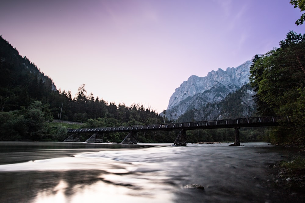 a bridge over a river with mountains in the background