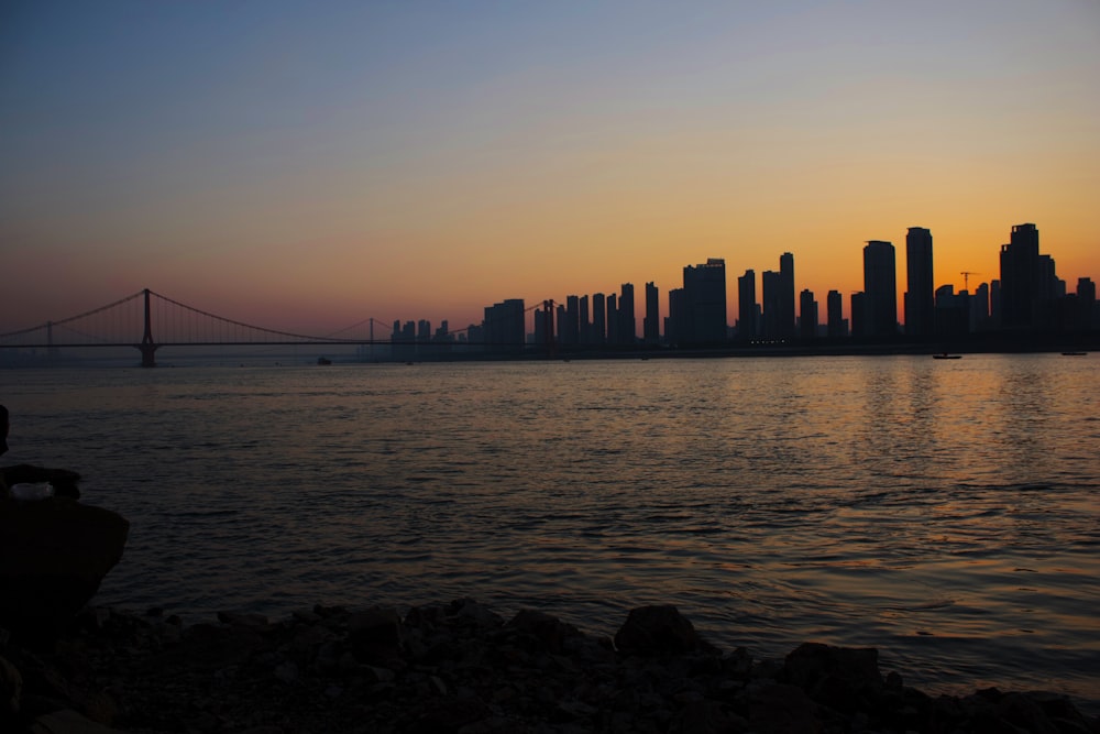 a man sitting on a bench watching the sun set over a city