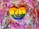 A heart-shaped object painted with the rainbow colors of the LGBTQ+ pride flag, featuring a prominent gold peace symbol in the center. The background is a vibrant and chaotic mix of bright pinks, purples, and oranges splattered with metallic silver and gold textures.