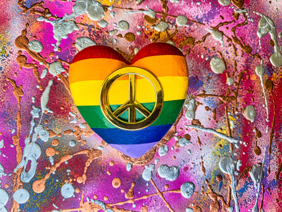 A colorful digital artwork celebrating queer pride with bold rainbow patterns and abstract shapes.