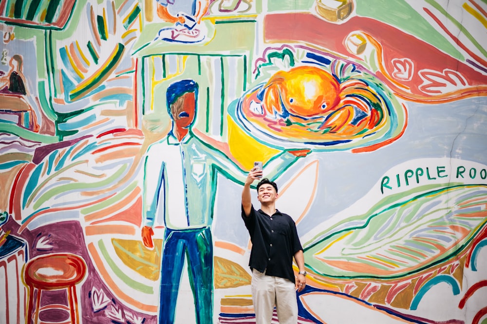 Un hombre parado frente a un colorido mural