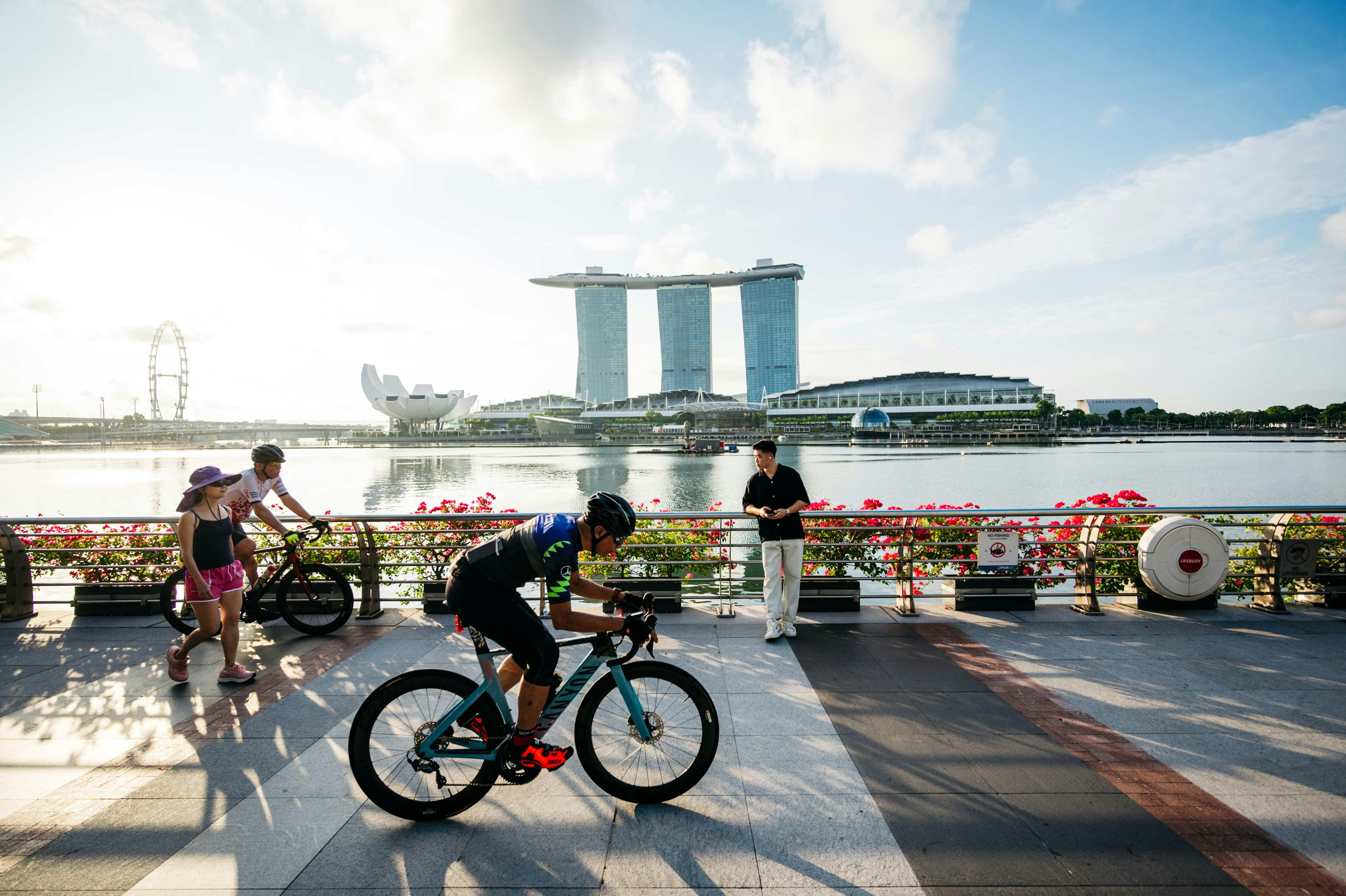 a man riding a bike down a sidewalk next to a river