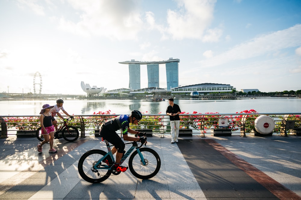 a man riding a bike down a sidewalk next to a river